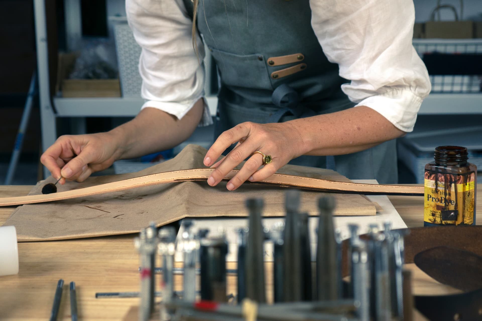 Rhiannon Thomas at her workbench finishing a leather edge